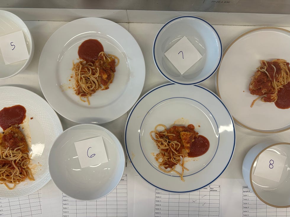 stain testing dinner plates with chicken parmesan, spaghetti and tomato sauce