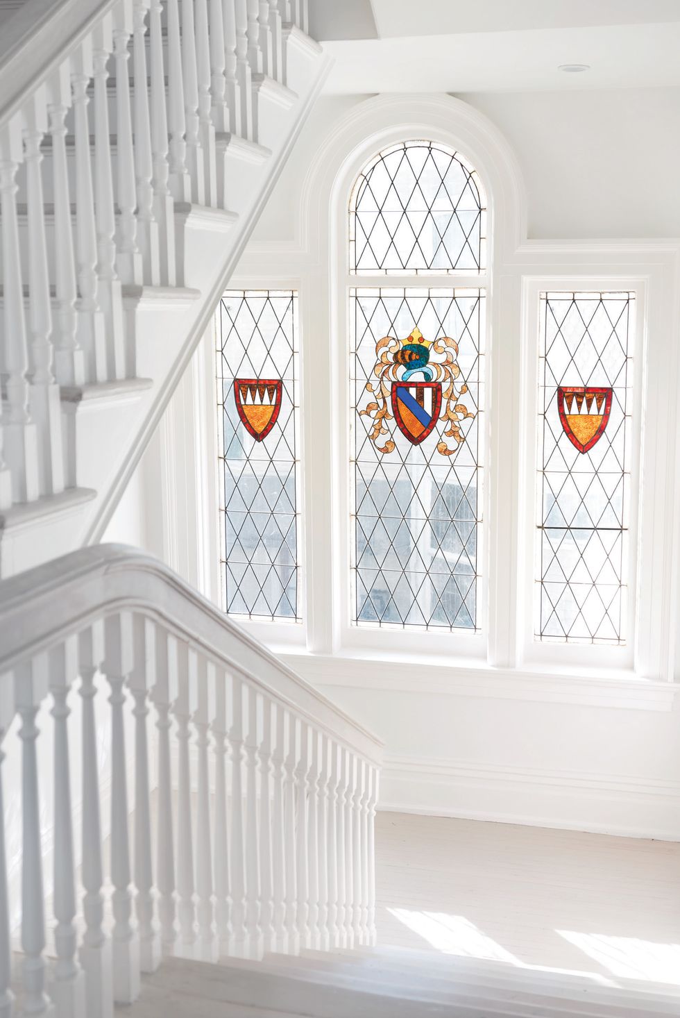 white hallway with stained glass windows of crest