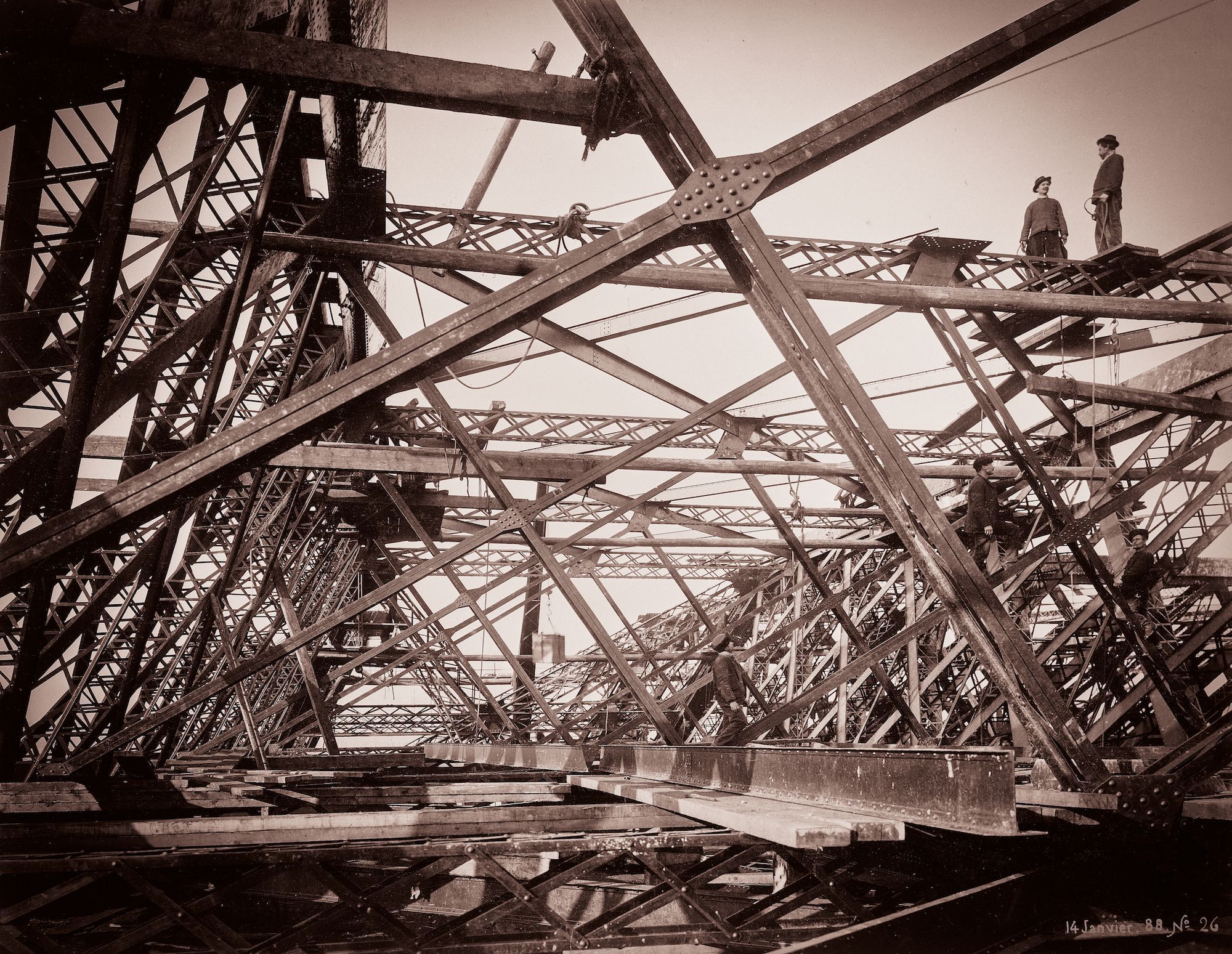 Arbeiders aan het werk bij de bouw van de Eiffeltoren Ze staan op de metalen liggers die deel uit maken van het bouwwerk