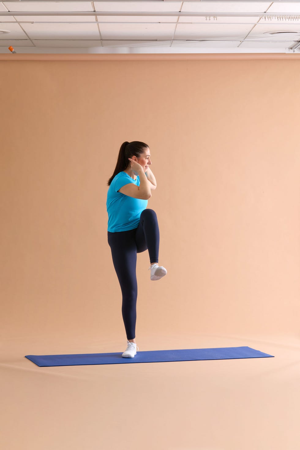 Person performing a fitness exercise on a yoga mat in a studio