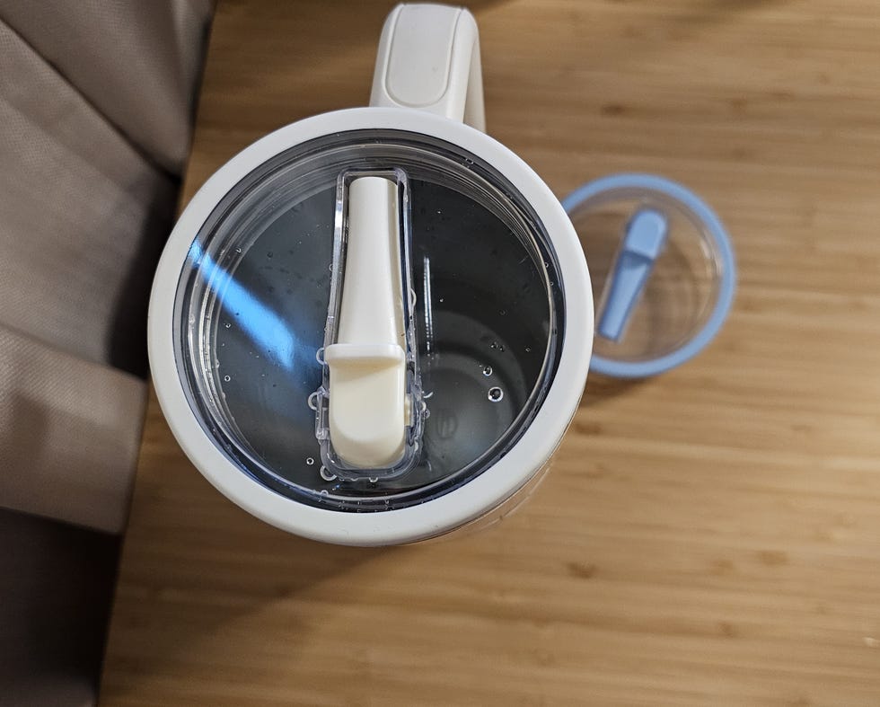 water bottle with a lid and straw placed on a wooden surface