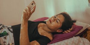 a woman looking at her phone and lying on a bed