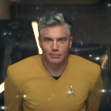 star trek strange new worlds, man in yellow uniform looking up at space