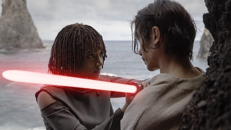 two characters engaged in a lightsaber confrontation at a rocky seaside in a scene from the acolyte