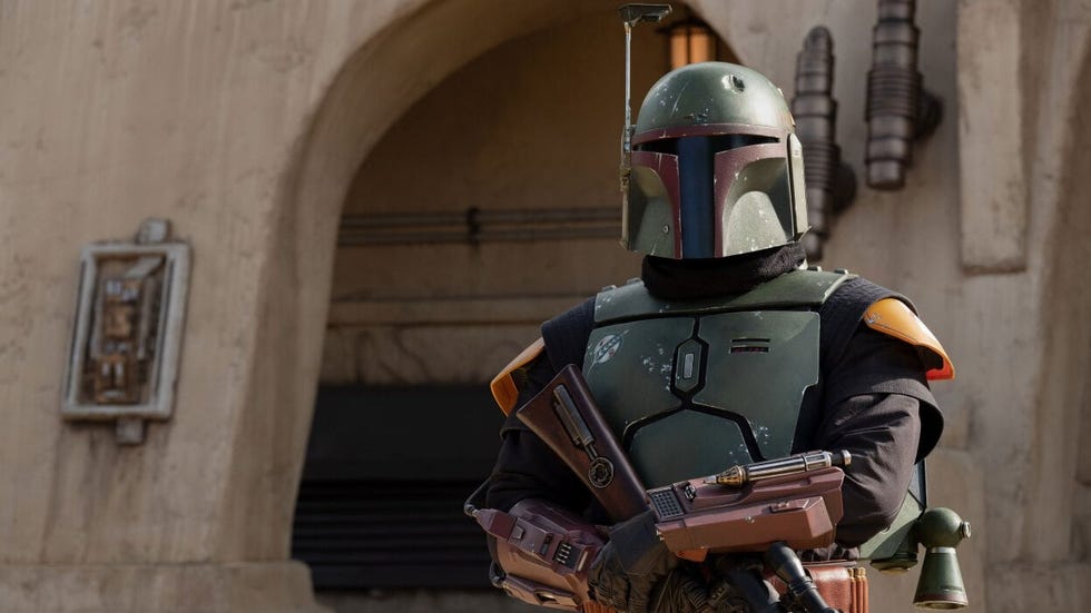 boba fett in armor wielding a blaster in an outdoor setting