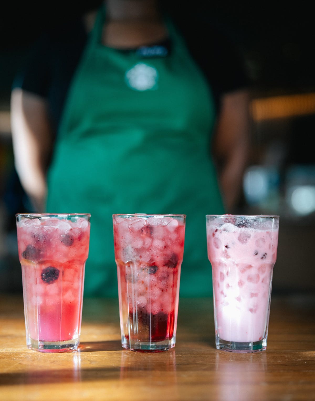 three colorful beverages in tall glasses on a wooden table