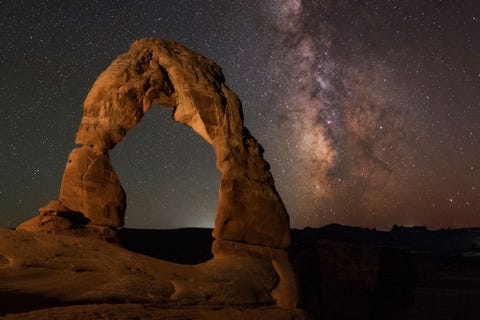 De Melkweg is te zien achter een sierlijke rotsboog in het Arches National Park