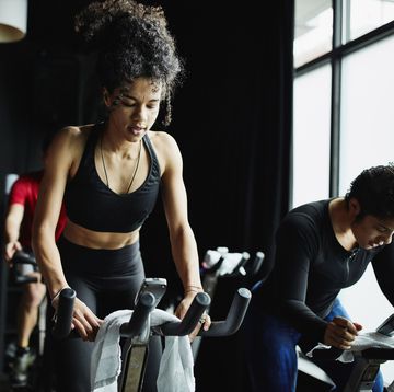 woman riding out of saddle during indoor cycling class in fitness studio