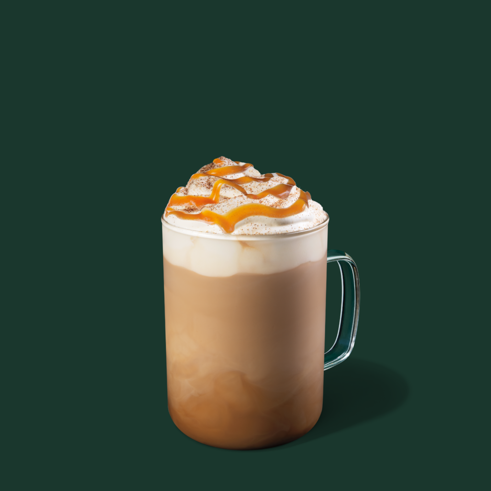a mug filled with layered coffee and cream topped with caramel drizzle