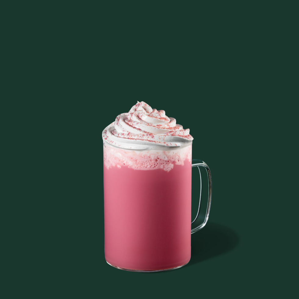 a pink beverage topped with whipped cream and red sprinkles in a glass mug