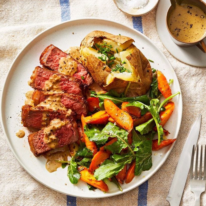 steak au poivre with a baked potato and carrot salad