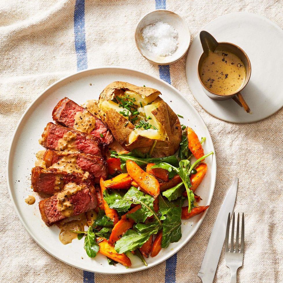 steak au poivre with side potato and salad on a white plate