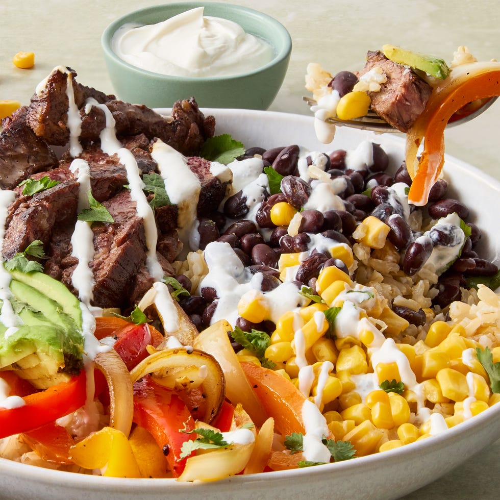 sliced steak with grilled peppers, corn, avocado, and black beans over rice