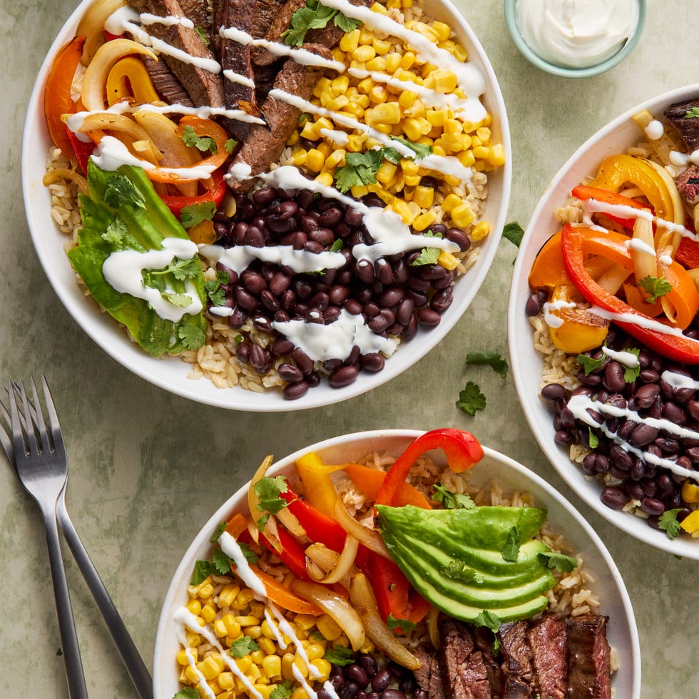 sliced steak with grilled peppers, corn, avocado, and black beans over rice