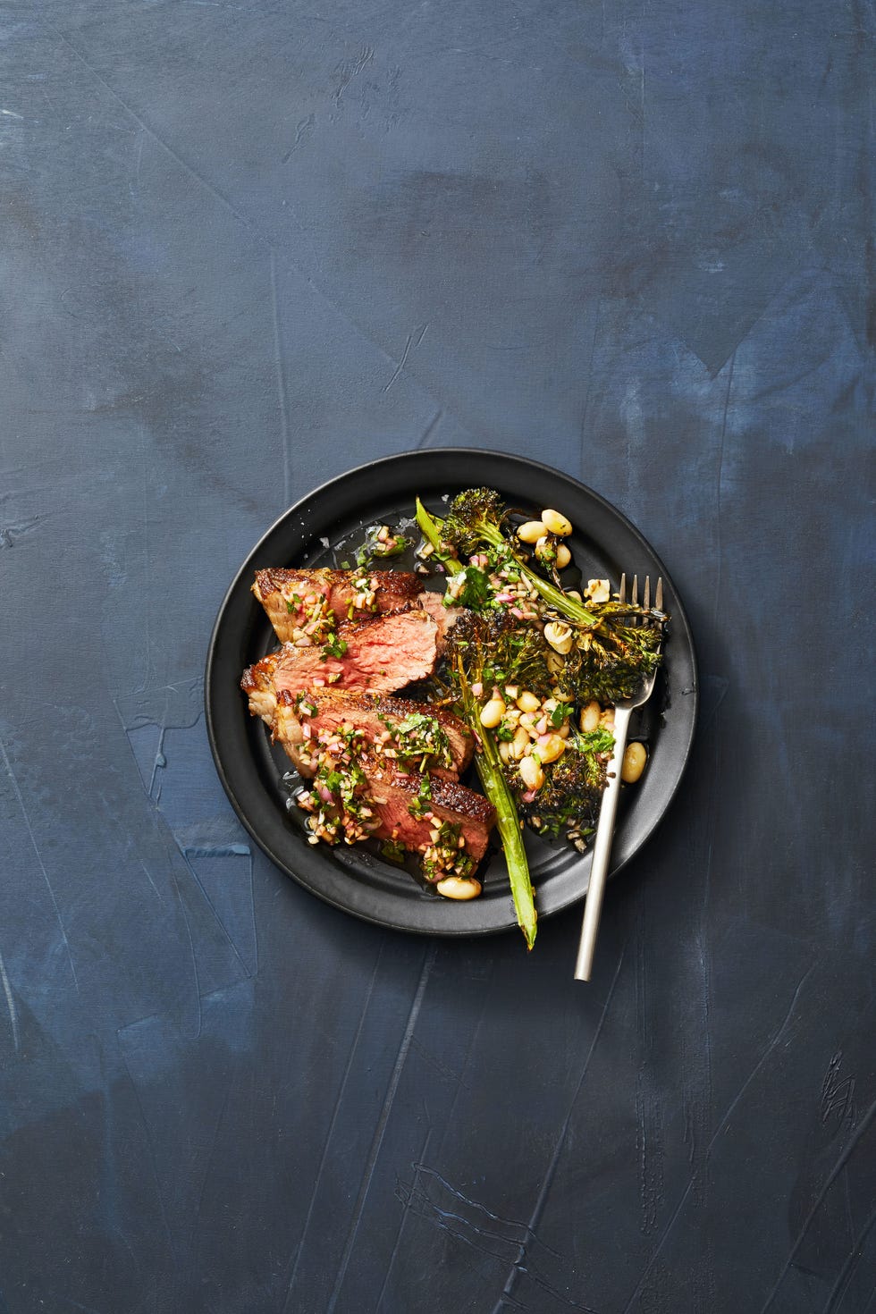 a plate with steak and broccolini and bean side