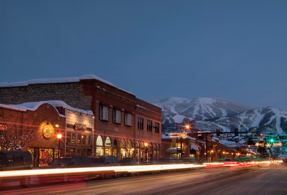 USA, Colorado, Steamboat Springs, Town at night with mountains in background a street with buildings and lights with snow in the background