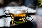 steaming hot tea cup in front of laptop for good housekeepings best tea story