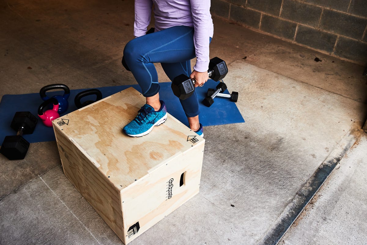 woman doing a rep of a step up with dumbbells, running injury