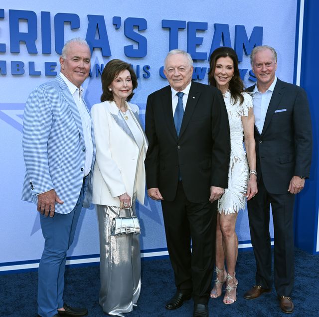 three men and two women stand together in a line on a blue carpet and pose for photos, behind them is a blue background that reads america's team
