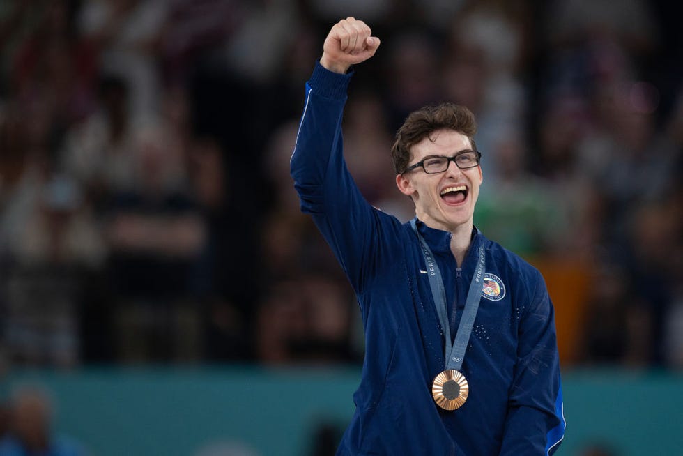 stephen nedoroscik wearing his usa olympic uniform and medal and holding his right arm in the air