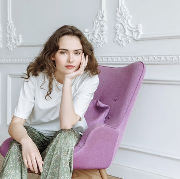 jonge vrouw poseert op een stoel in luxe kamer