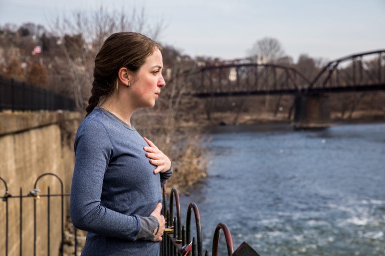 a runner taking a deep breath by a river