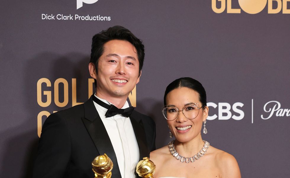 steven yeun y ali wong sosteniendo los premios globo de oro para los ganadores de la mejor actuación en un programa de televisión por carne de vacuno