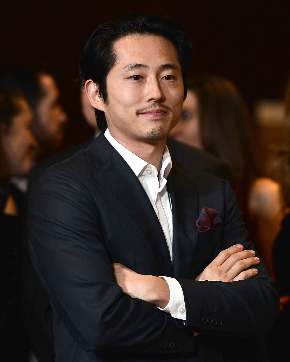 steven yeun standing with his arms folded