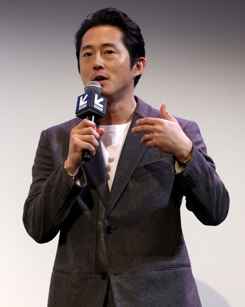 steven yeun talking and holding a microphone