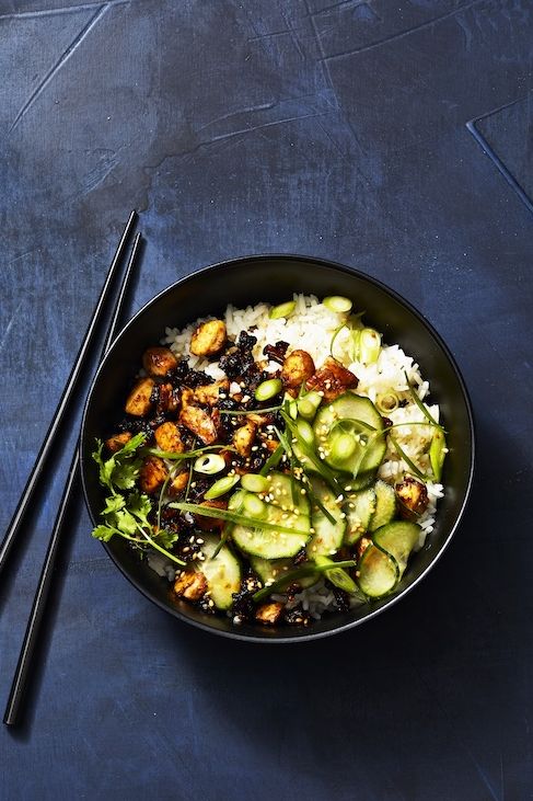 sticky tofu bowl with cucumber and rice in a black bowl