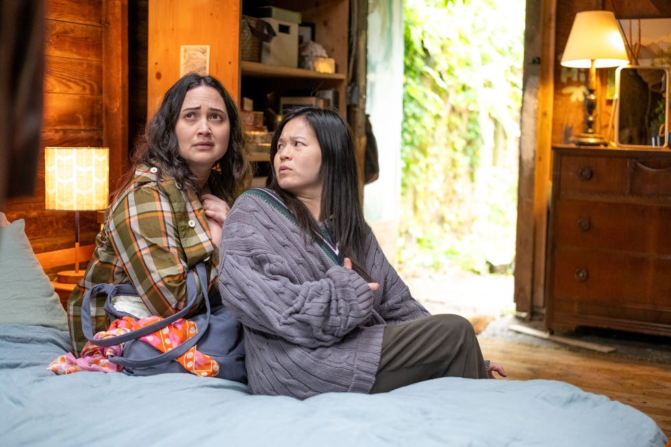 Two individuals sitting on a bed in a cozy rustic room