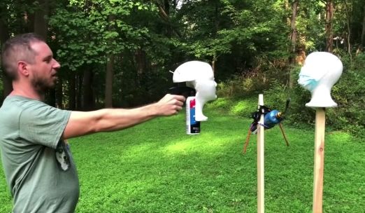 youtuber uncle rob holds a "coronavirus gun" and points it at another mannequin head with a mask on