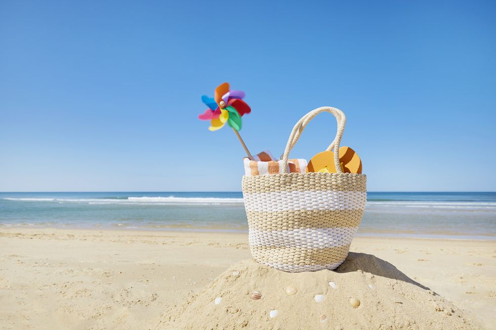 still life of beach bag and colorful pinwheel at sea against blue sky