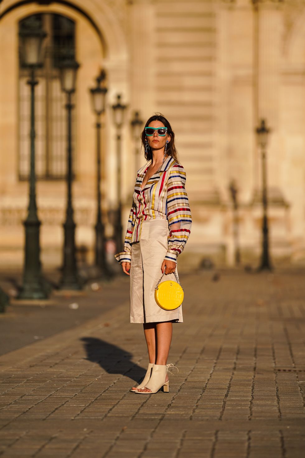 paris, france   august 03 natalia verza wears pucci sunglasses, bejeweled earrings, a colored striped shirt, a beige skirt, a yellow circular bag, beige leather boots, on august 03, 2020 in paris, france photo by edward berthelotgetty images