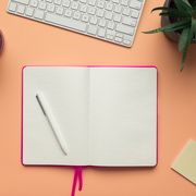 stock photo of an open notebook page with a pencil in a coral background
