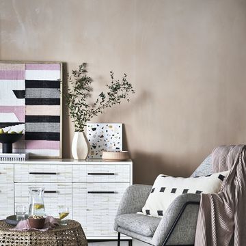 plaster pink walls in living room corner with armchair and sideboard storage