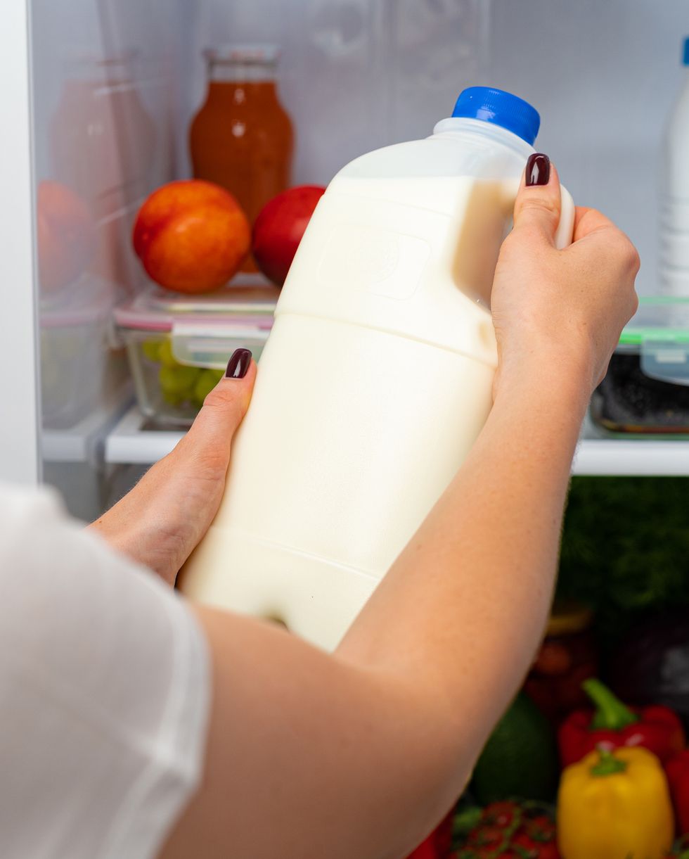 female hand taking bottle of milk from a fridge close up