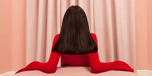 Red, Black, Pink, Curtain, Long hair, Interior design, Shoulder, Sitting, Tights, Window treatment, 