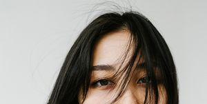 young asian female model with dark straight hair wearing white top looking at camera against white background