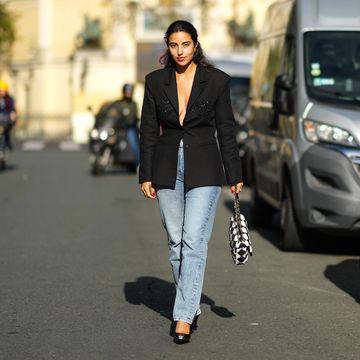 paris, france september 29 bettina looney wears a gold large earring, a black blazer jacket with sequined yoke, high waist blue faded large denim jeans pants, a black and white checkered pattern handbag from chanel, black shiny leather pointed pumps heels shoes, rings, outside cecilie bahnsen, during paris fashion week womenswear spring summer 2022, on september 29, 2021 in paris, france photo by edward berthelotgetty images