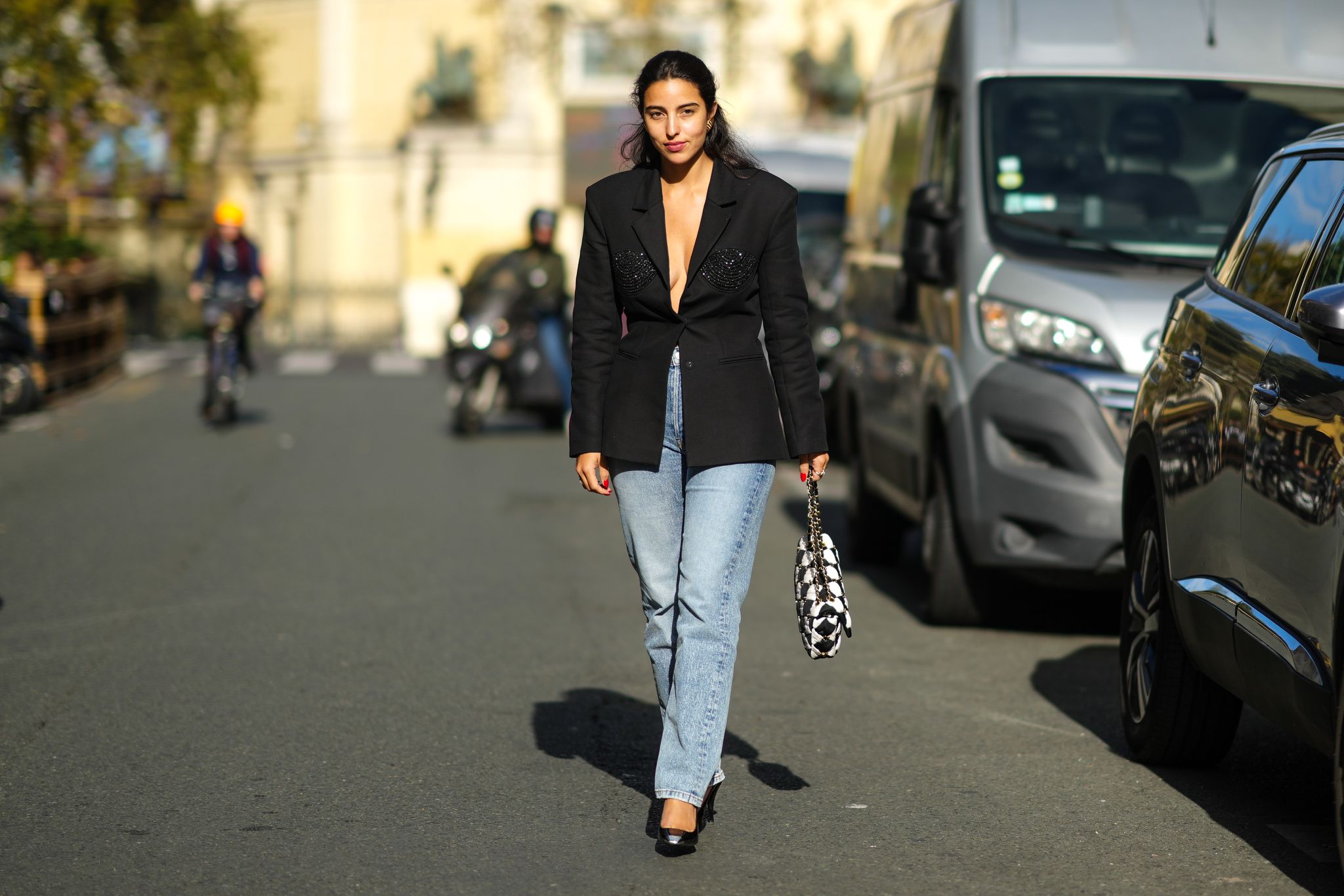 paris, france september 29 bettina looney wears a gold large earring, a black blazer jacket with sequined yoke, high waist blue faded large denim jeans pants, a black and white checkered pattern handbag from chanel, black shiny leather pointed pumps heels shoes, rings, outside cecilie bahnsen, during paris fashion week womenswear spring summer 2022, on september 29, 2021 in paris, france photo by edward berthelotgetty images