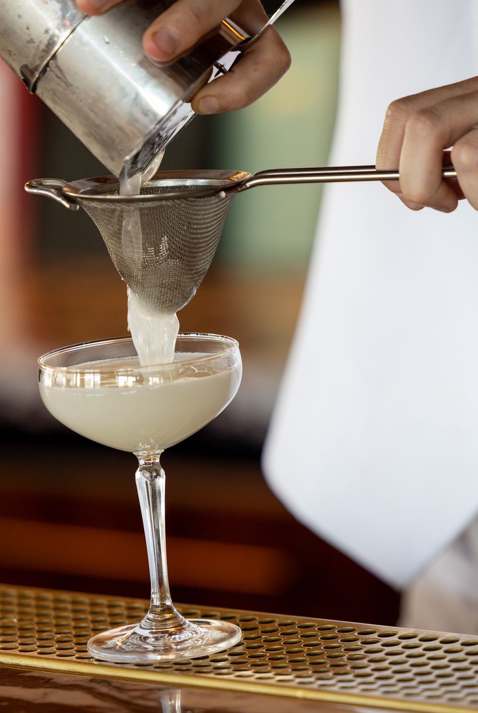 straining a cocktail into a coupe