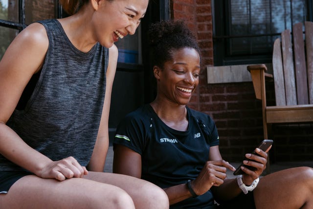 twee vrouwen bekijken hun strava activiteit na een rondje hardlopen