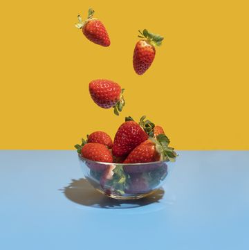 strawberries flying in the bowl on the blue yellow background