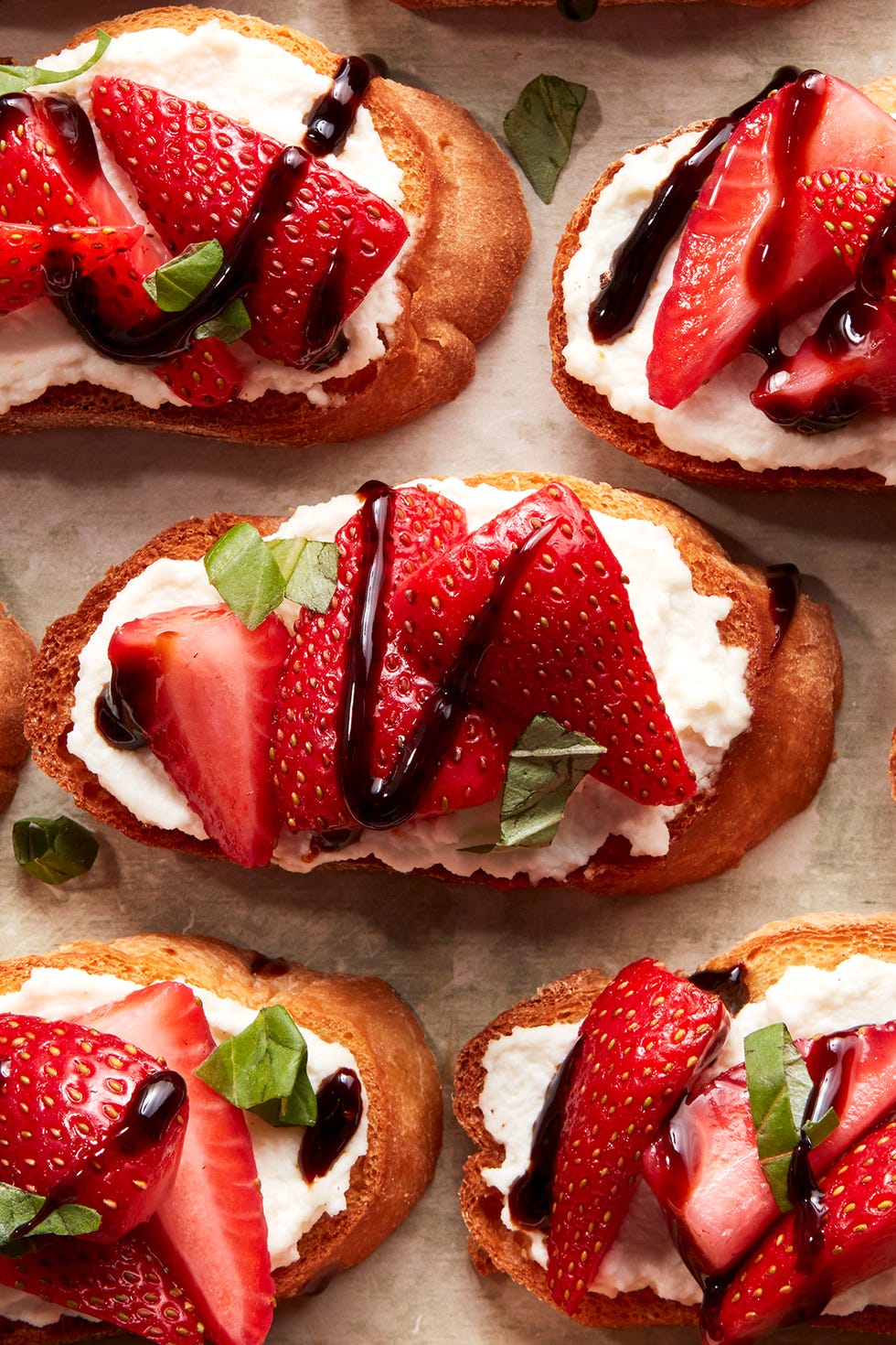 sliced strawberries on top of ricotta spread on crostini drizzled with balsamic