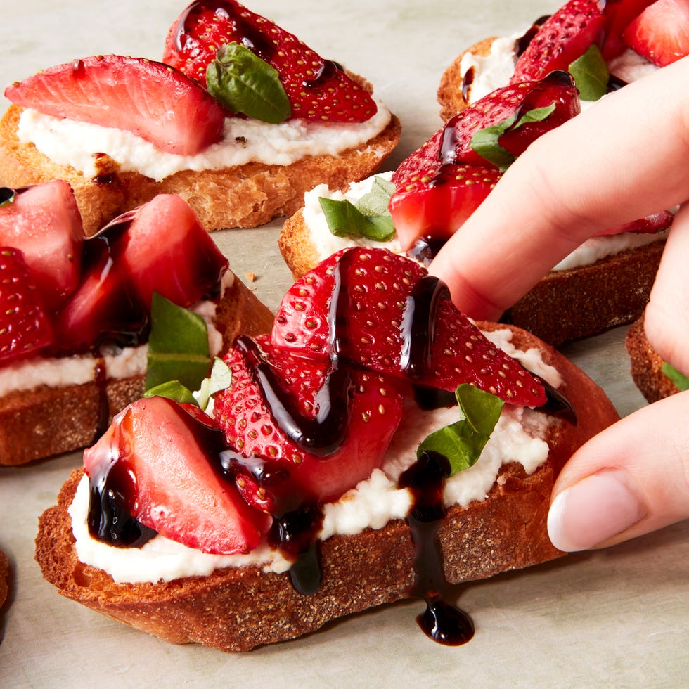 sliced strawberries on top of ricotta spread on crostini drizzled with balsamic