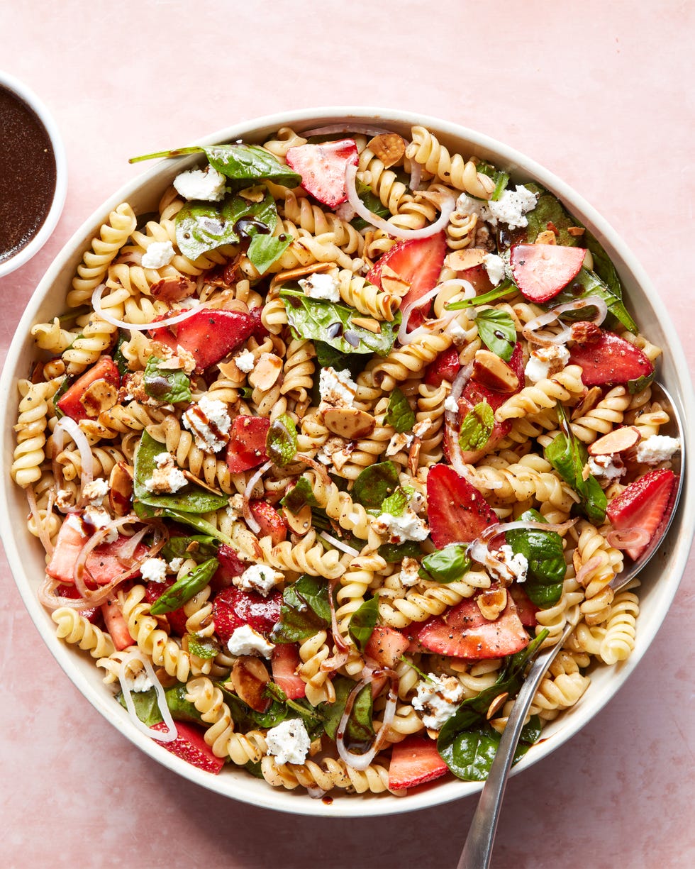 pasta salad tossed with spinach, sliced strawberries, cheese, and balsamic dressing