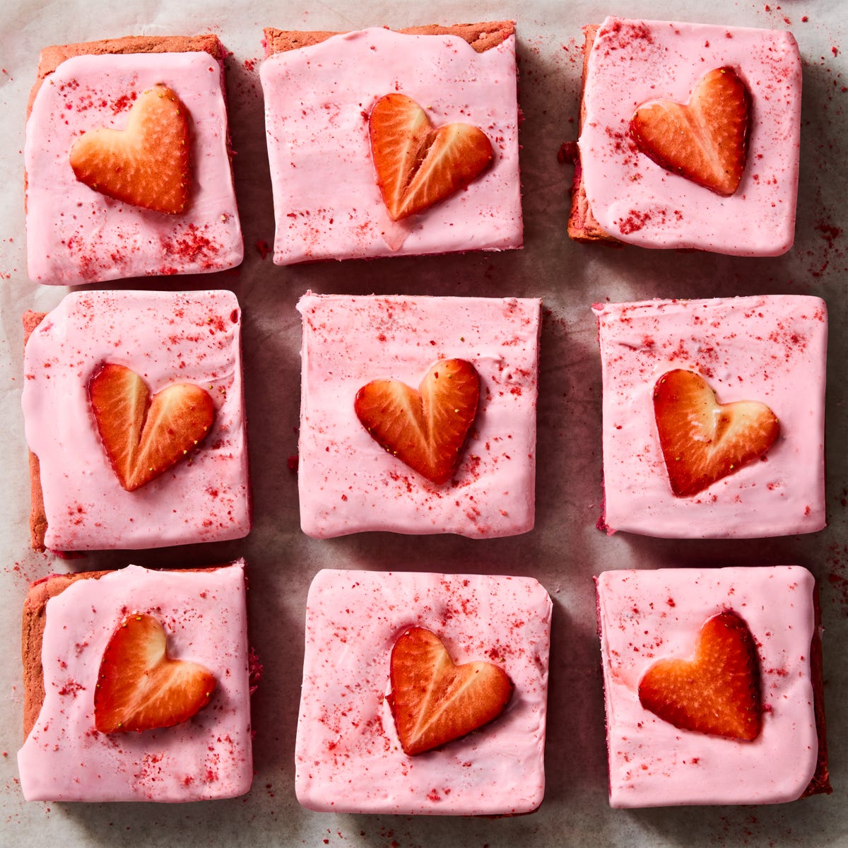 pink brownies topped with pink icing and strawberry hearts