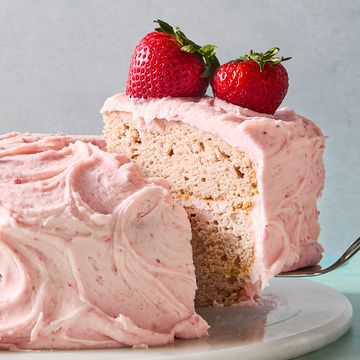 layered strawberry cake with pink icing and a strawberry on top