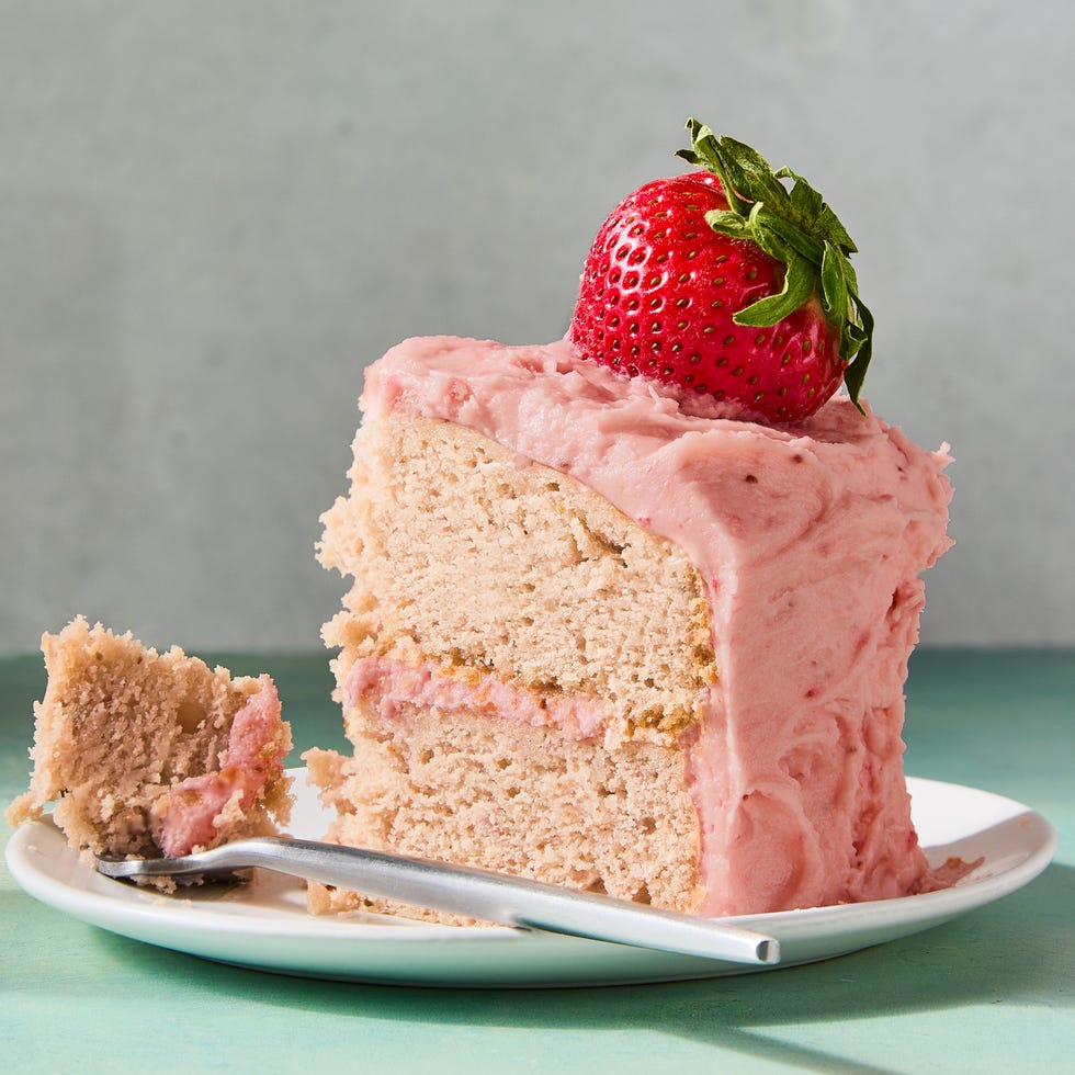 strawberry cake with icing and topped with whole strawberries